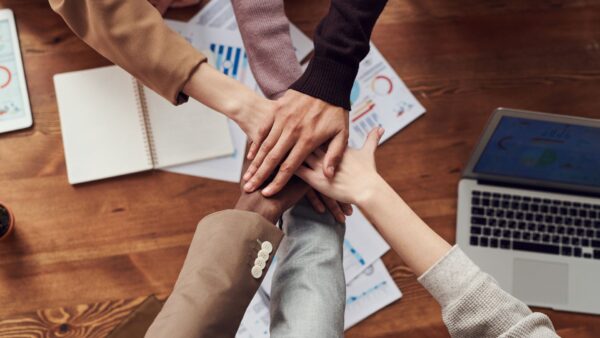 Group of people placing their hands together in a show of unity and teamwork