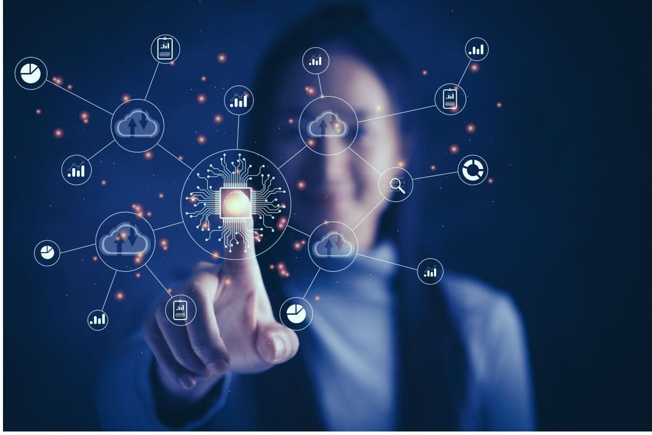 A person in a dark environment pointing at a digital network of interconnected cloud and communication icons