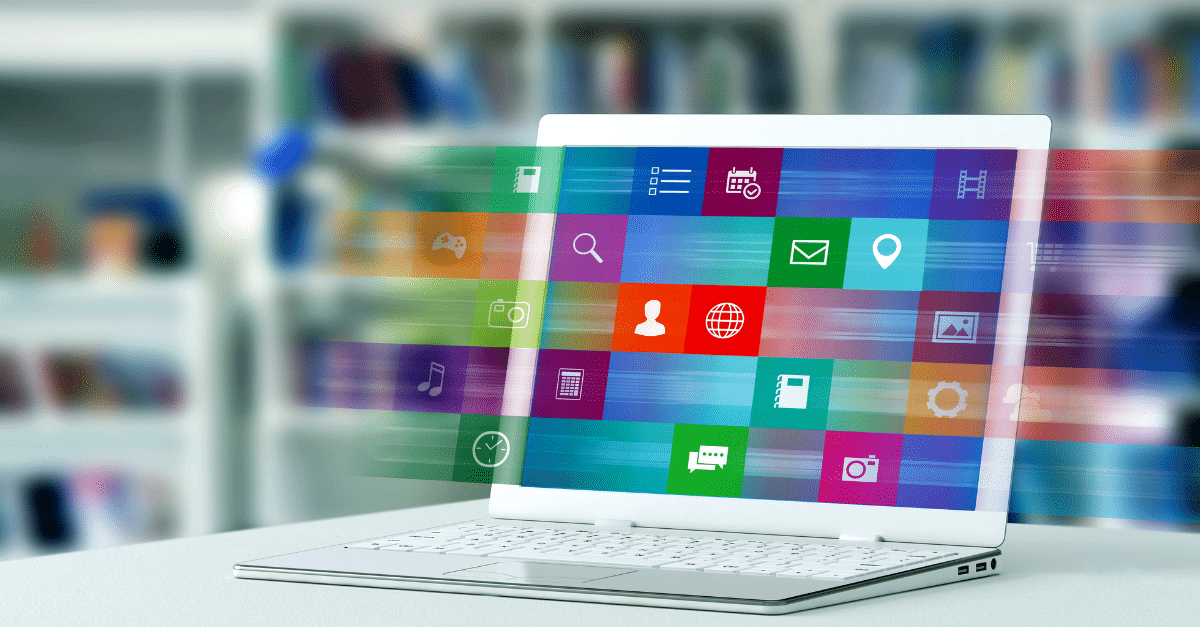 A laptop on a desk displaying colorful, transparent application icons floating above the screen