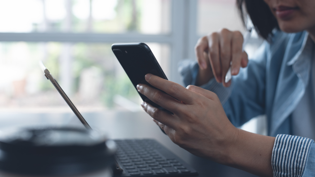 Woman working on a laptop and looking at a cell phone